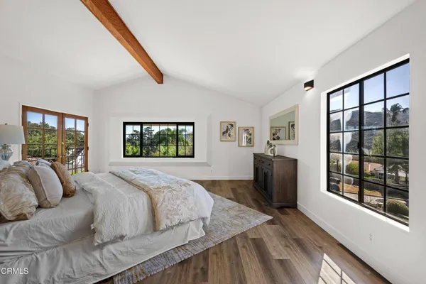 a view of a hallway with wooden floor and a bathroom