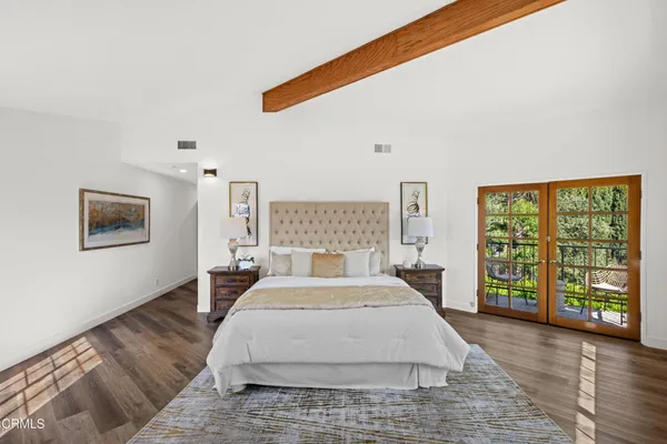 a view of a patio with a table and chairs under an umbrella with large trees