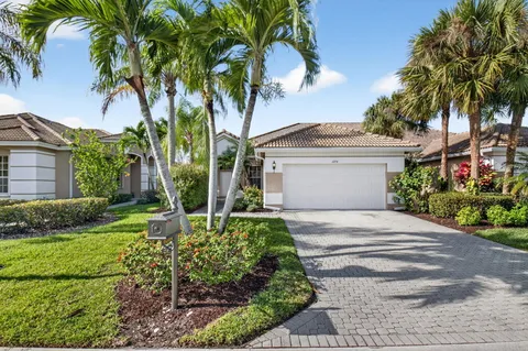 a front view of a house with a garden and palm trees