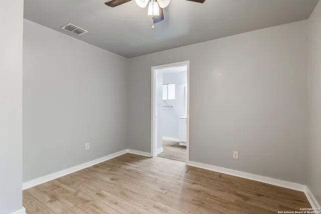 an empty room with wooden floor chandelier fan and windows