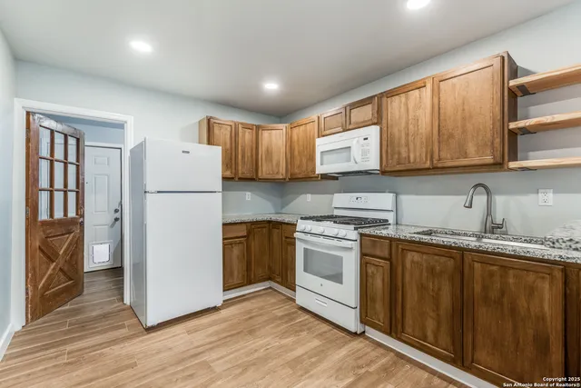 a kitchen with granite countertop wooden cabinets a refrigerator and a sink