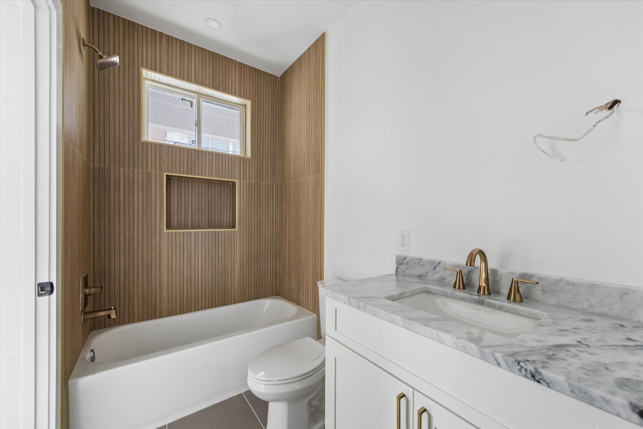 1034 West 17th Street, Unit B Houston, TX 77008 - Photo 13 of 25 Ensuite bath for the second bedroom features dolomite countertops, wood-look tile, and a shower/tub combo.