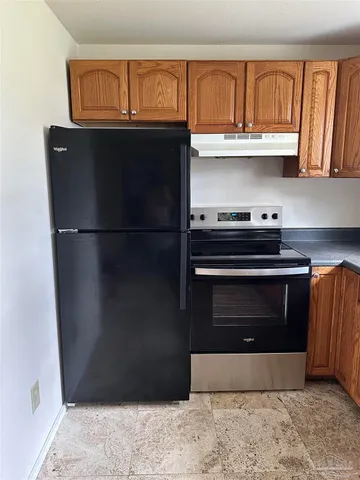 a kitchen with granite countertop a stove and a refrigerator