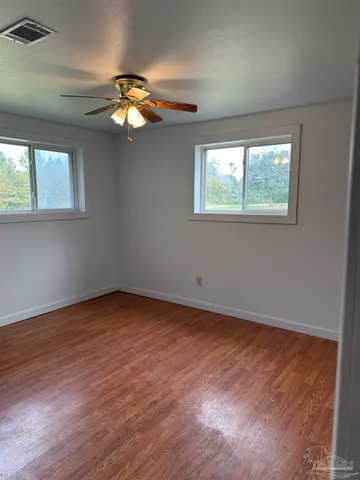 a view of empty room with wooden floor and fan