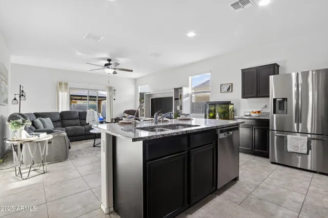 a open kitchen with stainless steel appliances granite countertop a sink dishwasher stove refrigerator and cabinets