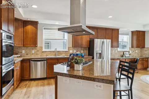 a kitchen with stainless steel appliances a dining table chairs refrigerator and sink