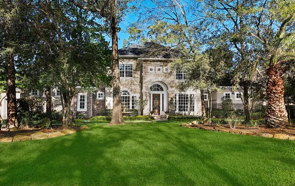 a view of a white house with a big yard and large trees
