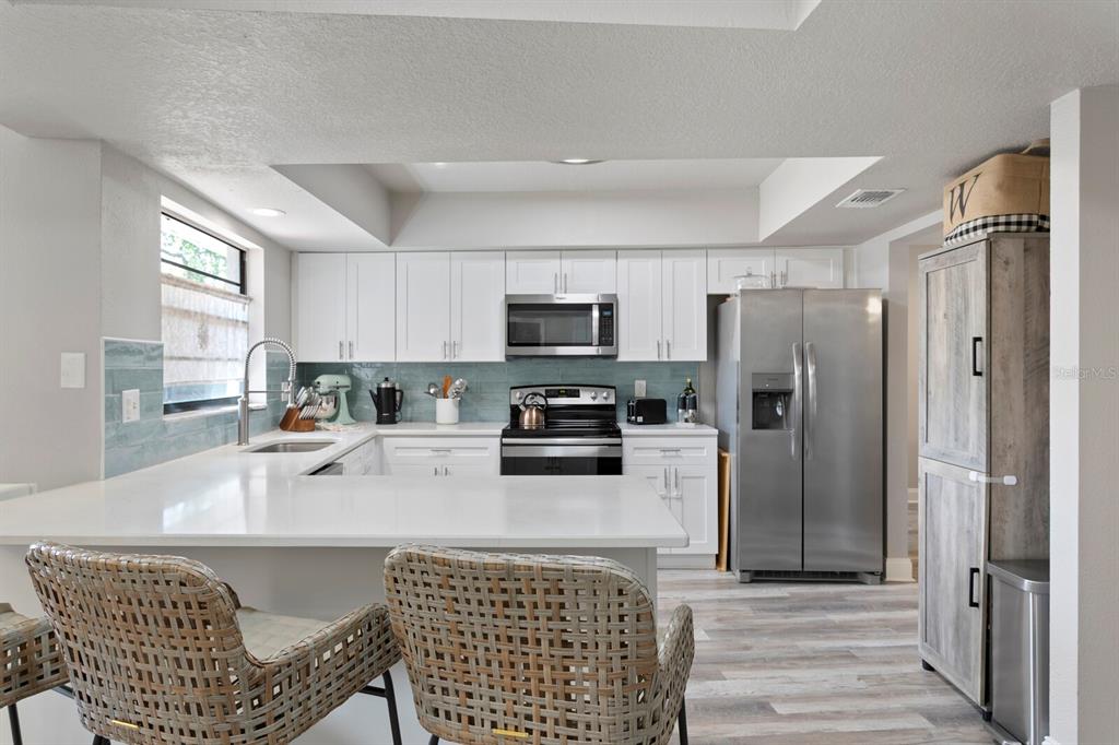 6712 Jennifer Drive Temple Terrace, FL 33617 - Photo 8 of 30 a kitchen with stainless steel appliances a refrigerator a stove a sink a dining table and chairs