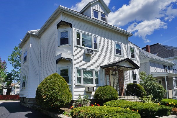 150 Brown Street, Unit 1L Waltham, MA 02453 - Photo 1 of 11 a view of a white house next to a yard