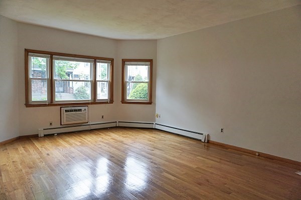 150 Brown Street, Unit 1L Waltham, MA 02453 - Photo 8 of 11 an empty room with wooden floor and windows