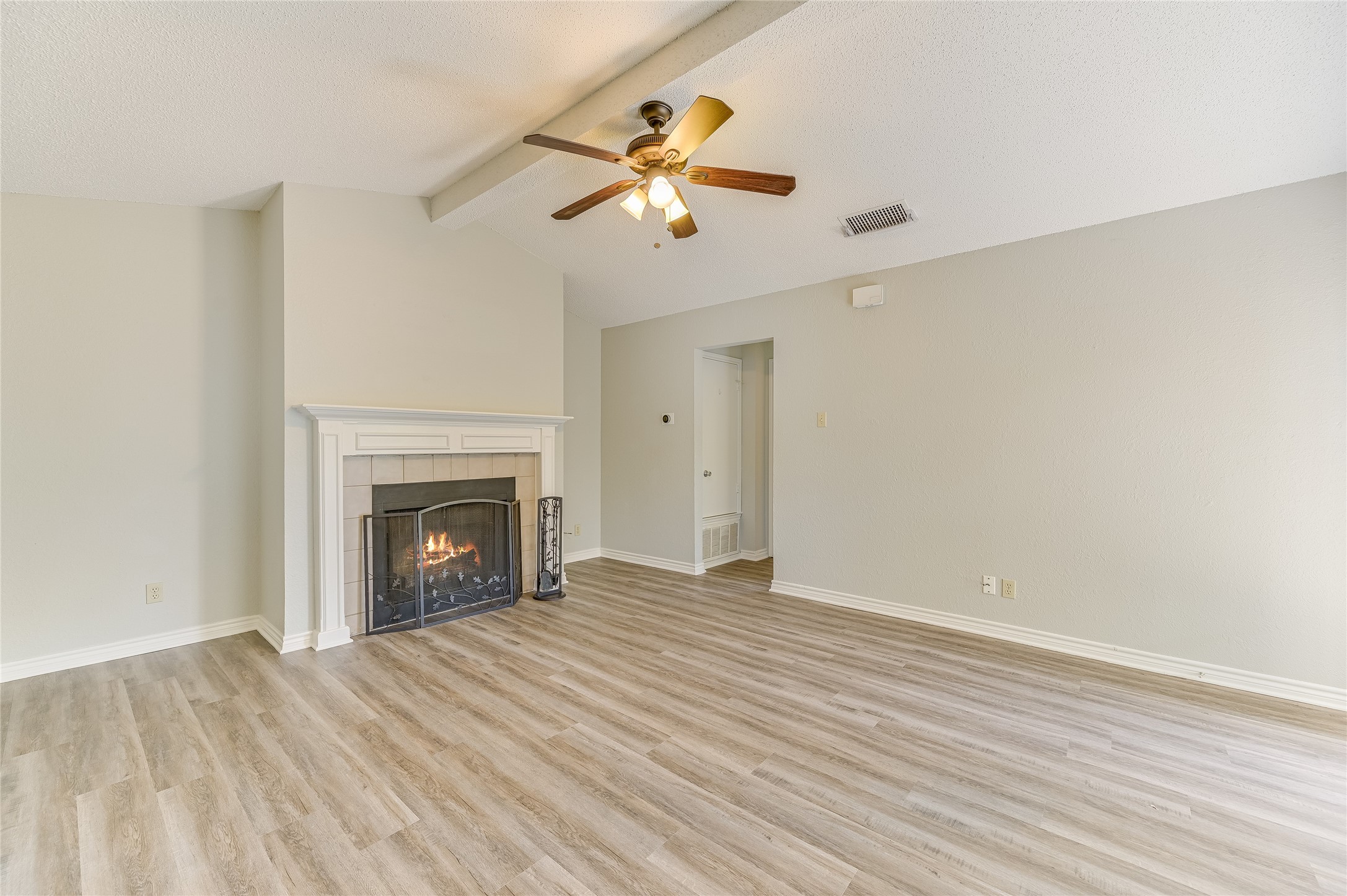526 Cutty Trail, Unit B Lakeway, TX 78734 - Photo 4 of 10 Living area featuring a fireplace with a white mantel, light-toned wood-finish flooring, and a ceiling fan with integrated lighting