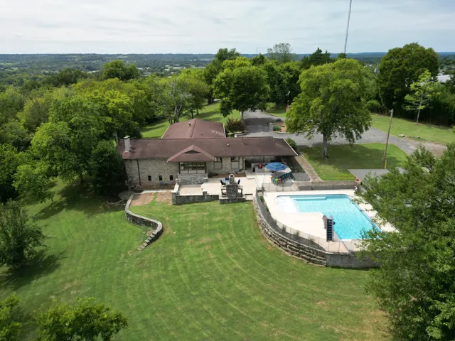 an aerial view of a house with swimming pool a yard and lake view