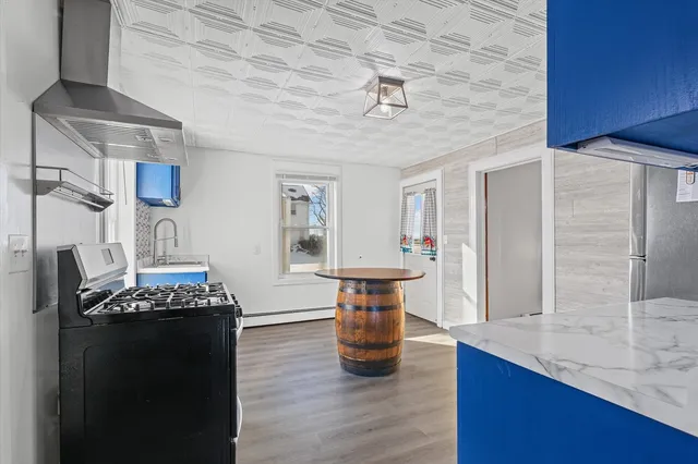 a kitchen with granite countertop stainless steel appliances a counter space a sink and a wooden floor