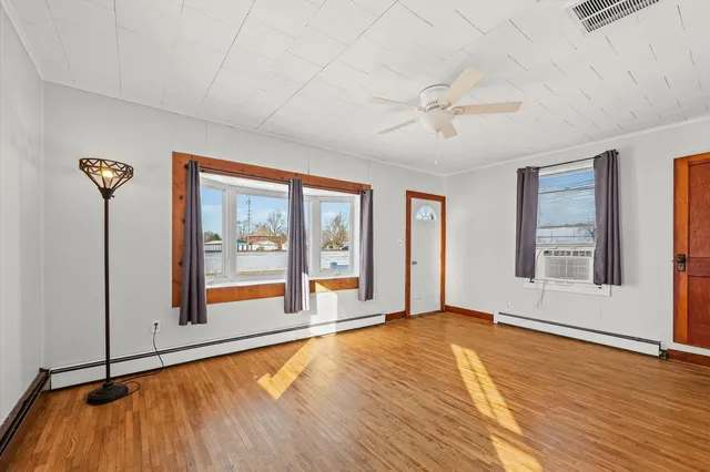 a view of an empty room with a window and wooden floor
