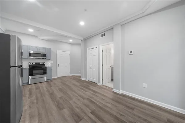 a view of a kitchen with wooden floor electronic appliances and cabinets