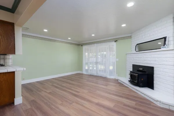 a view of an empty room with wooden floor and windows