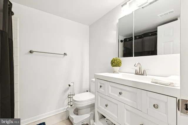 a bathroom with a granite countertop sink vanity mirror and toilet