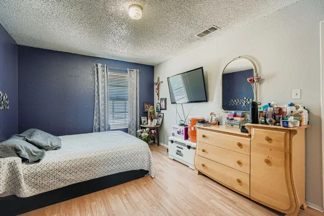 a bedroom with a bed and a flat tv screen on dresser