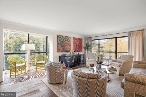 a living room with furniture large windows and wooden floor