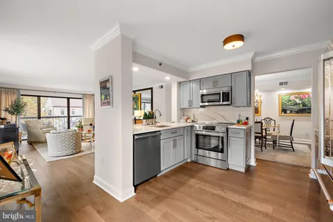 a kitchen with stainless steel appliances granite countertop a stove top oven a sink dishwasher a dining table and chairs with wooden floor