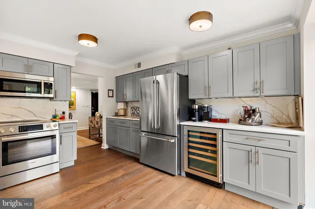 a kitchen with granite countertop a refrigerator oven a sink dishwasher and white cabinets with wooden floor