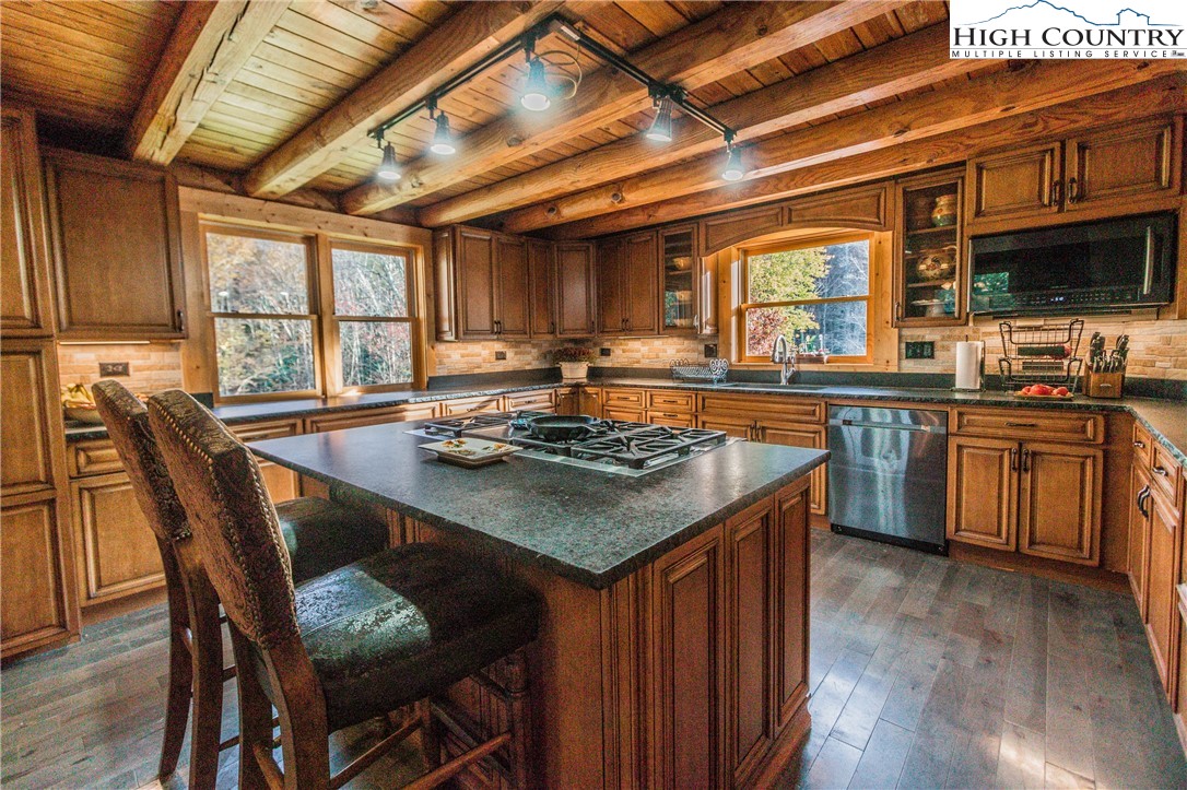 3654 Andy Hicks Road Banner Elk, NC 28604 - Photo 29 of 40 a kitchen with a stove a sink dishwasher a dining table and chairs with wooden floor
