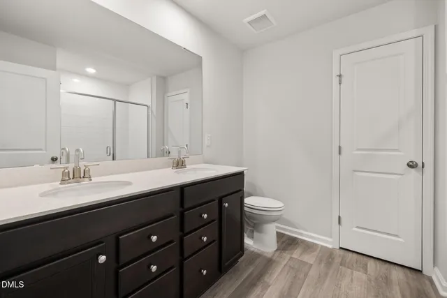 a bathroom with a double vanity sink toilet and a mirror