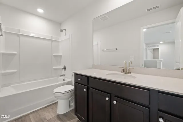 a bathroom with a granite countertop sink toilet mirror and bathtub