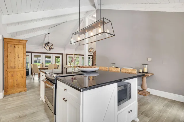 a kitchen that has a sink a stove and a table with wooden floor
