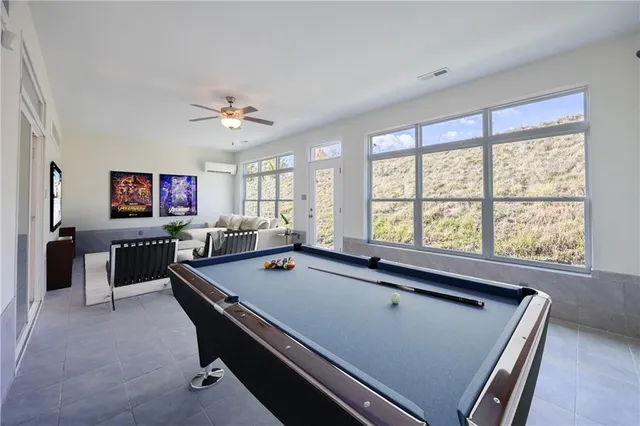 a room with furniture pool table flat screen tv and windows