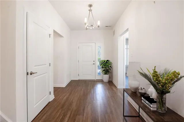a view of a hallway with wooden floor and a chandelier