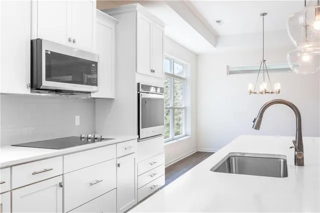 a kitchen with stainless steel appliances granite countertop a sink a microwave cabinets and a wooden floor