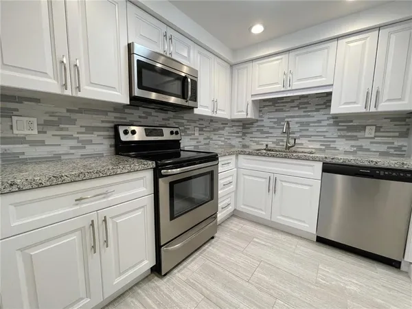 a kitchen with white cabinets stainless steel appliances and sink