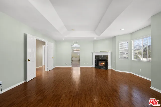 a view of an empty room with wooden floor fireplace and a window