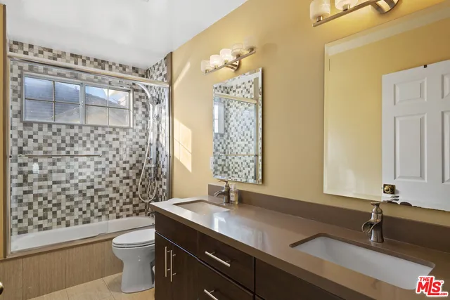 a bathroom with a granite countertop sink a toilet a mirror and shower