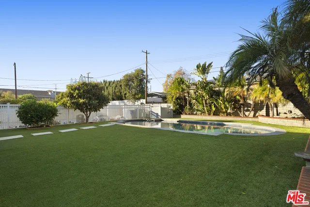a view of a house with a small yard and a large parking space