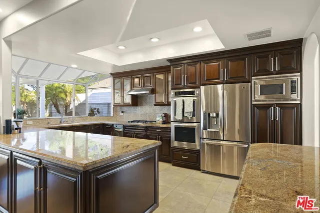 a kitchen with stainless steel appliances granite countertop a refrigerator a sink and a stove