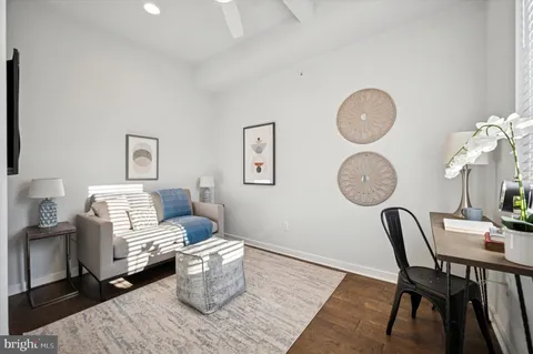 a living room with furniture a rug and wall paintings
