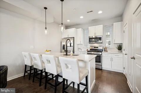 a kitchen with stainless steel appliances a white table chairs refrigerator and microwave