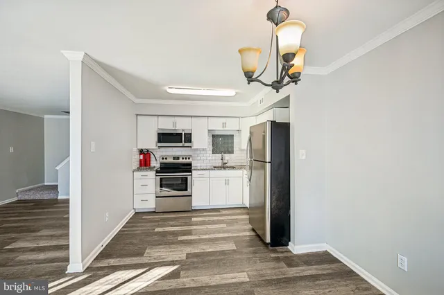 a view of a hallway with wooden floor and a cabinet