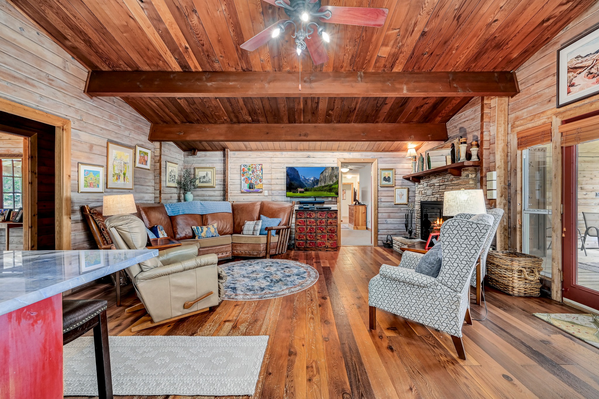 900 Box Canyon Road Wimberley, TX 78676 - Photo 5 of 40 Living room with wood walls, vaulted ceiling with beams, Pine floors and a wood burning fireplace.