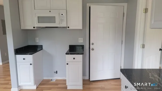 a view of kitchen with stainless steel appliances wooden floor and cabinets