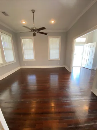 an empty room with wooden floor windows and ceiling fan
