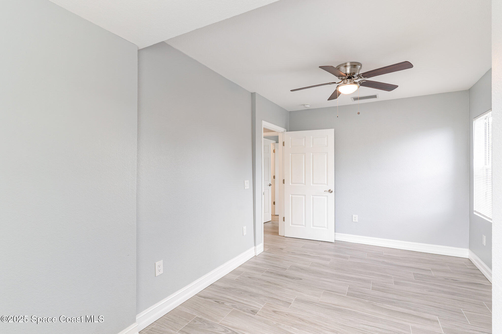 2566 Spence Drive Northeast Palm Bay, FL 32905 - Photo 16 of 20 a view of a big room with wooden floor and chandelier fan