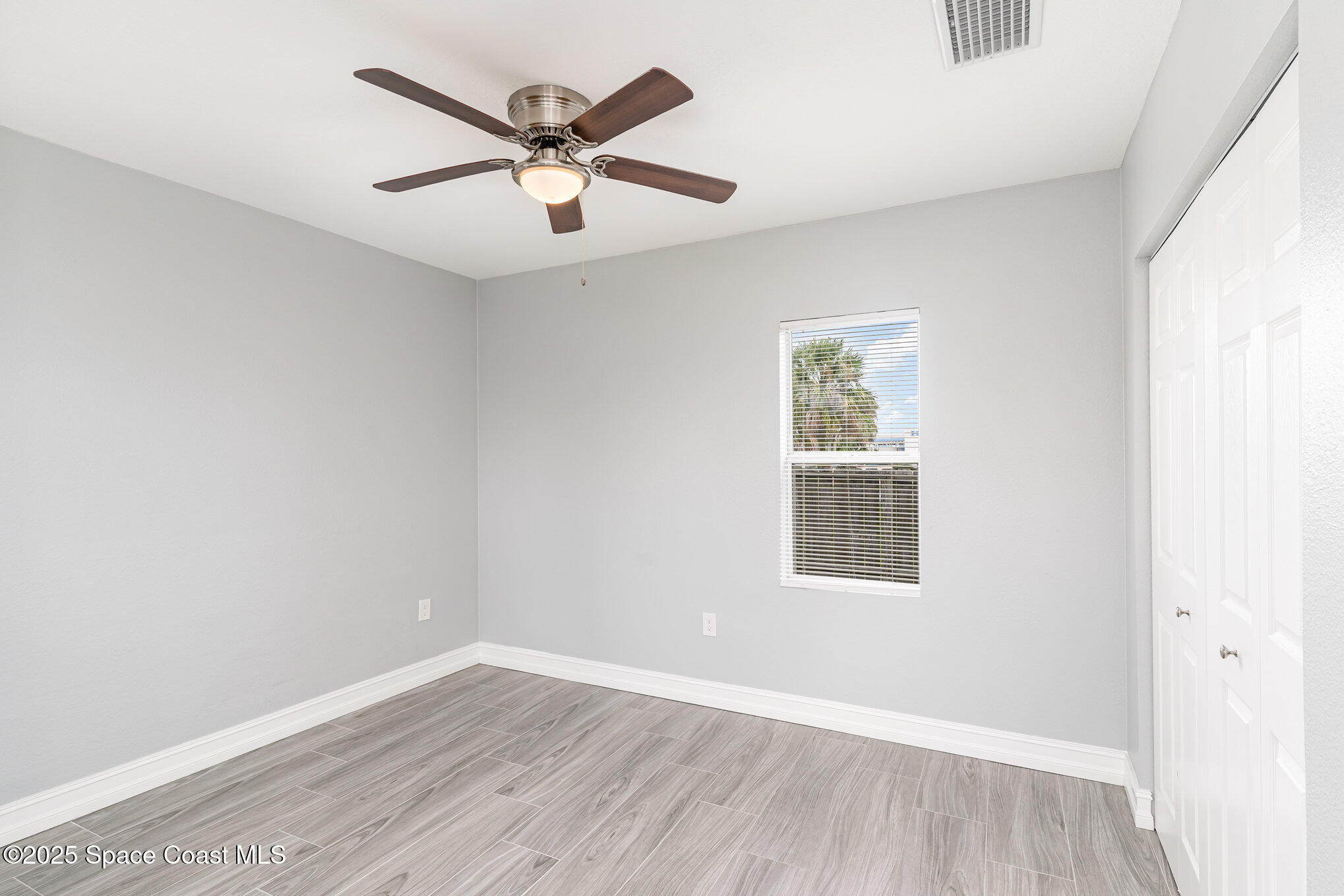2566 Spence Drive Northeast Palm Bay, FL 32905 - Photo 17 of 20 an empty room with wooden floor ceiling fan and windows