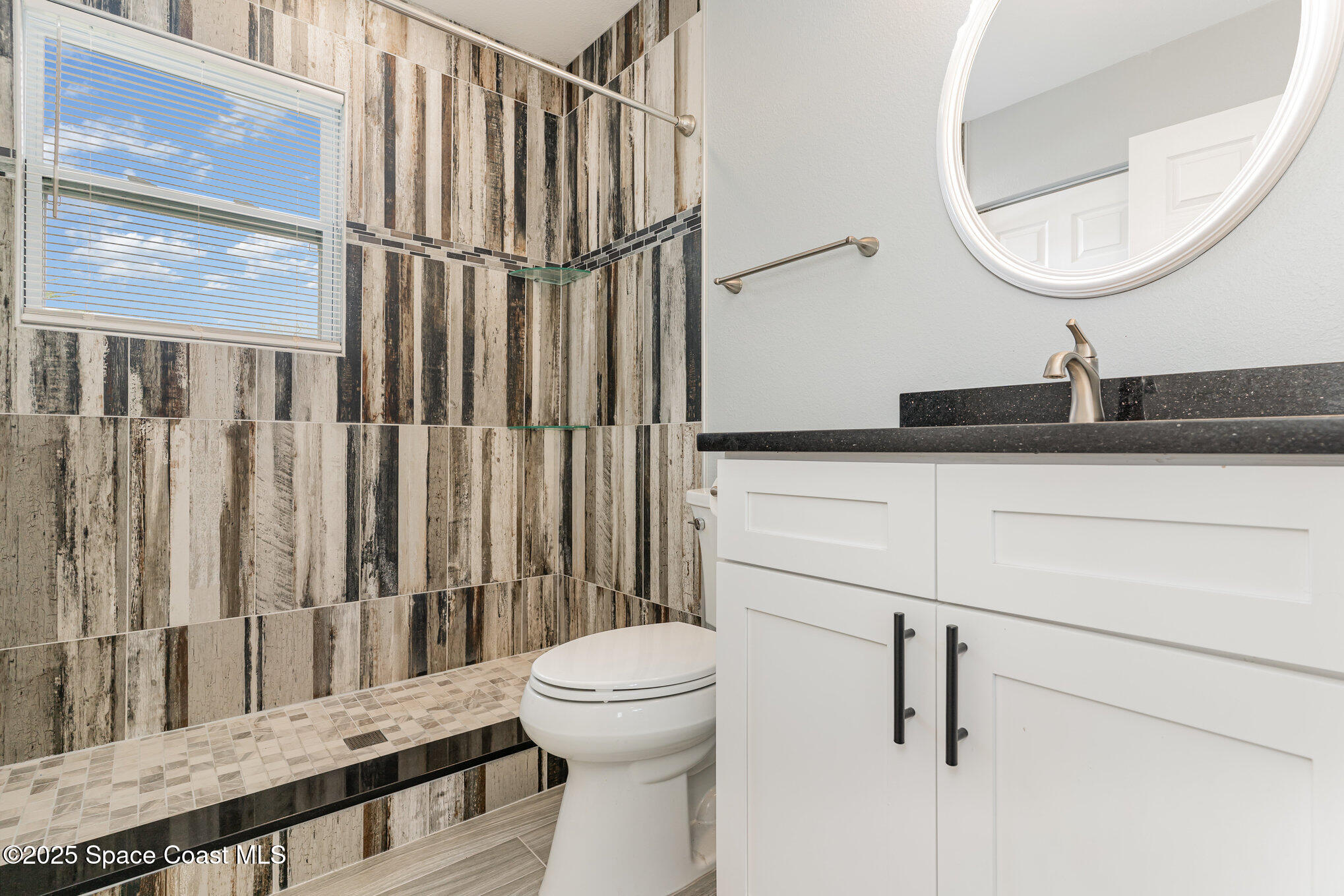 2566 Spence Drive Northeast Palm Bay, FL 32905 - Photo 18 of 20 a bathroom with a sink a toilet and a mirror