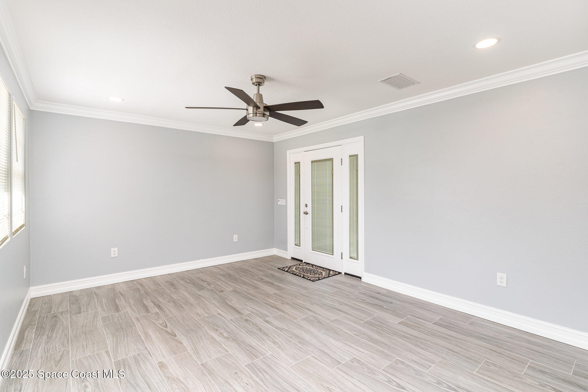 2566 Spence Drive Northeast Palm Bay, FL 32905 - Photo 4 of 20 an empty room with wooden floor and windows