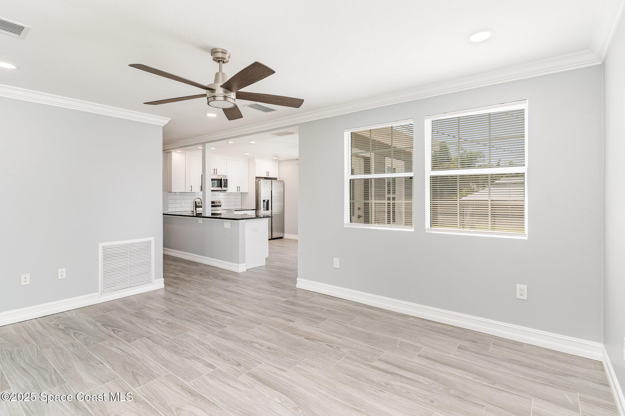 2566 Spence Drive Northeast Palm Bay, FL 32905 - Photo 6 of 20 a view of a kitchen with a stove cabinets a ceiling fan and wooden floor