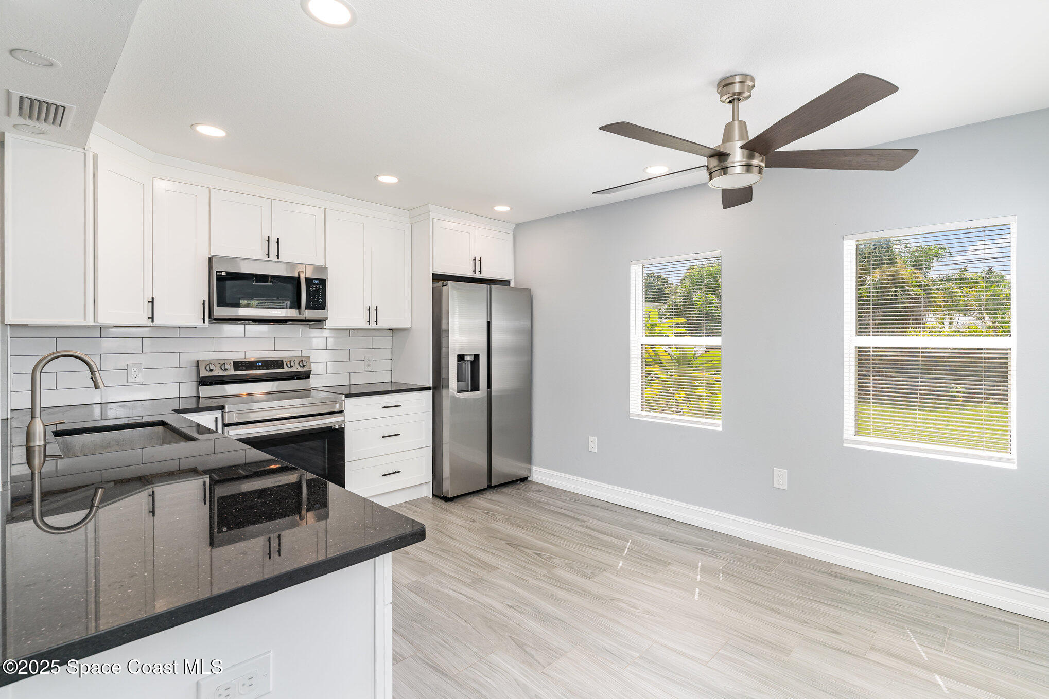 2566 Spence Drive Northeast Palm Bay, FL 32905 - Photo 7 of 20 a kitchen with stainless steel appliances granite countertop a stove a sink a refrigerator a window a island and white cabinets