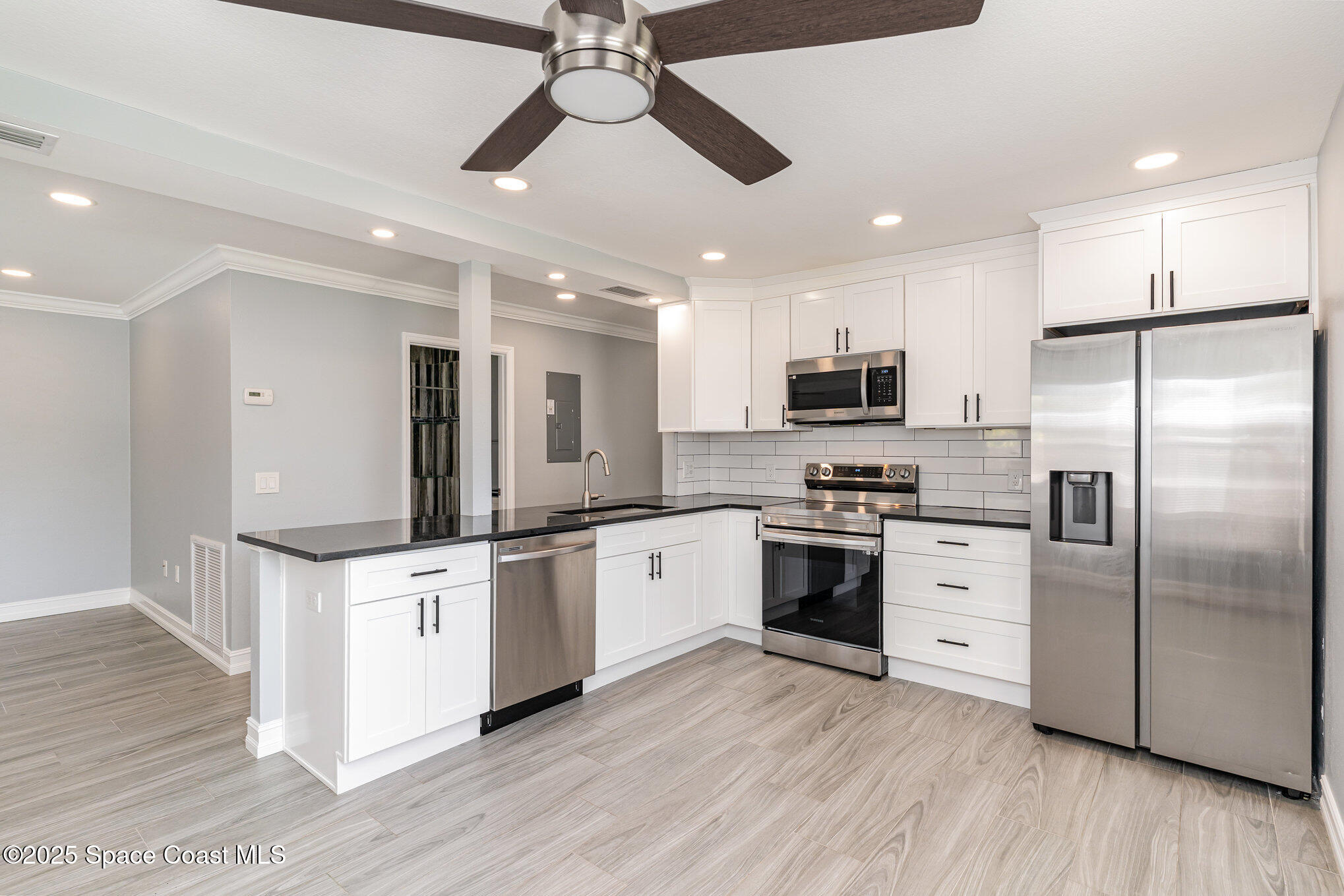 2566 Spence Drive Northeast Palm Bay, FL 32905 - Photo 8 of 20 a kitchen with stainless steel appliances kitchen island granite countertop a stove top oven a refrigerator a sink and a refrigerator